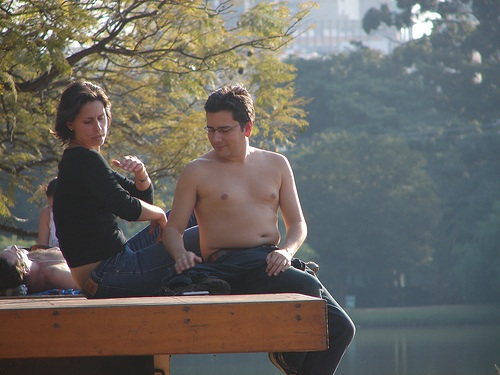 lady and man with no shirt sit on dock